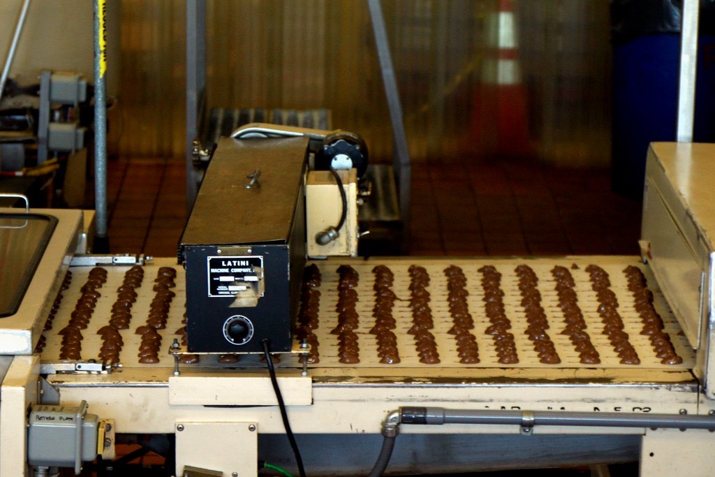 Depositor head running product across a flat belt line